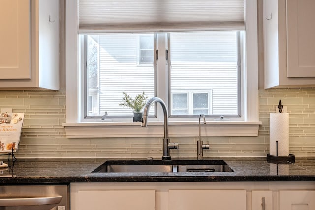 kitchen featuring backsplash, stainless steel dishwasher, white cabinetry, and a sink