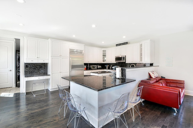 22328 N Prairie Ct, Kildeer, IL 60047 - kitchen featuring appliances with stainless steel finishes, a breakfast bar area, decorative backsplash, glass insert cabinets, and dark wood-style floors