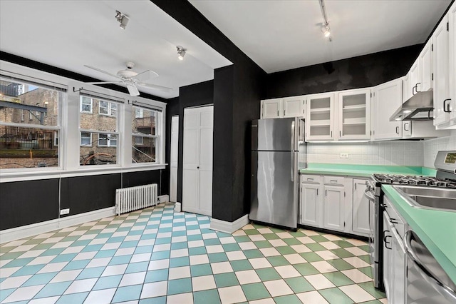 kitchen featuring track lighting, plenty of natural light, appliances with stainless steel finishes, under cabinet range hood, and radiator heating unit