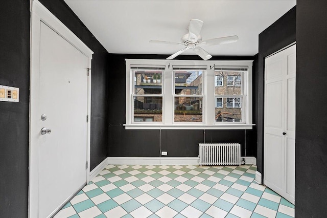 entryway with radiator, baseboards, a ceiling fan, and light floors