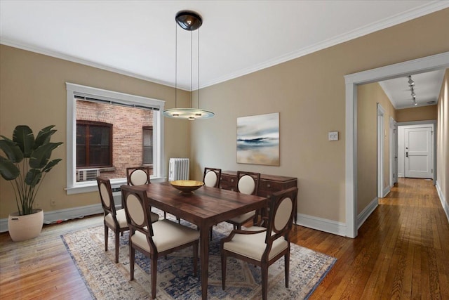 dining space featuring wood-type flooring, baseboards, and ornamental molding