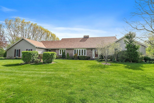 ranch-style house featuring brick siding, a chimney, and a front lawn