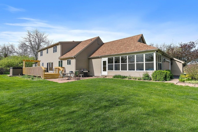 back of house with an attached garage, a shingled roof, a lawn, and a wooden deck