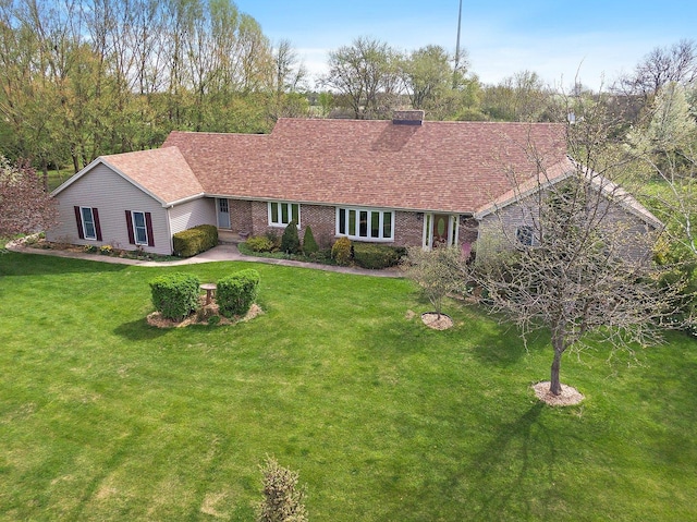 single story home featuring brick siding, a front lawn, and a chimney