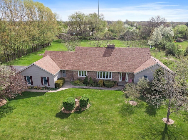 view of front of home featuring brick siding, a chimney, and a front yard