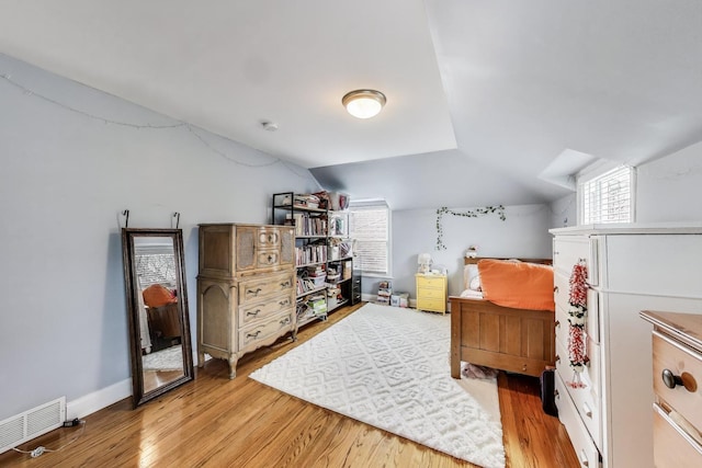 bedroom featuring light wood-type flooring, vaulted ceiling, and multiple windows