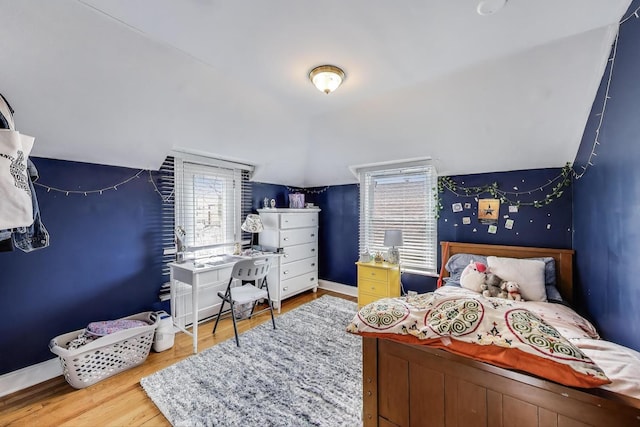 bedroom with lofted ceiling, wood finished floors, and baseboards