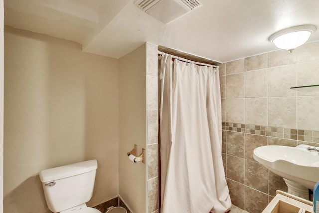 full bath with toilet, visible vents, and a tile shower
