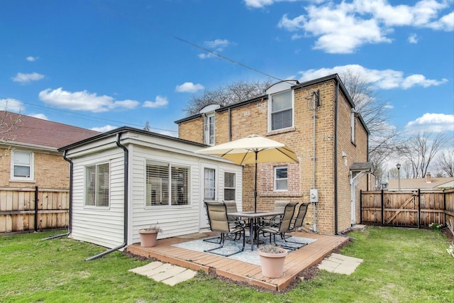rear view of house with a lawn, a fenced backyard, outdoor dining space, and a deck