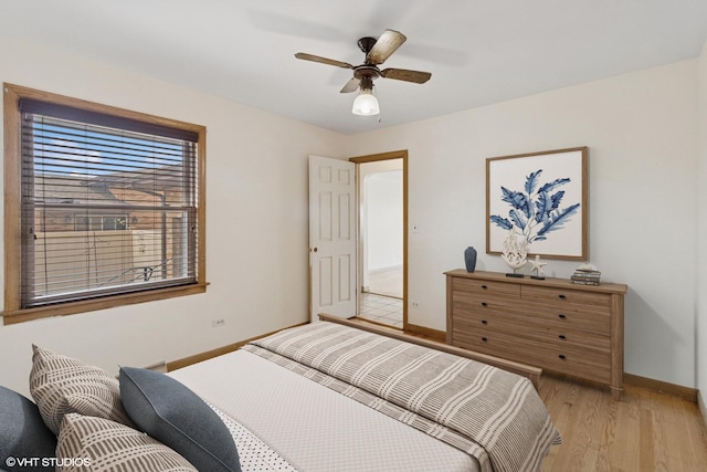bedroom with ceiling fan, light wood-style floors, and baseboards