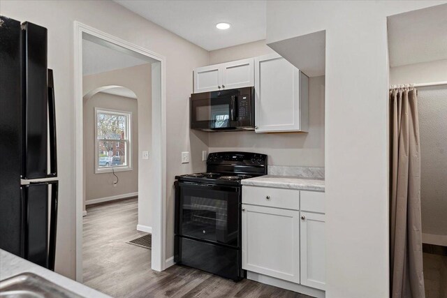 1980 W Forest Ave, Decatur, IL 62522 - kitchen featuring white cabinets, baseboards, arched walkways, black appliances, and wood finished floors
