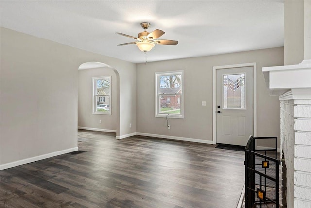 1980 W Forest Ave, Decatur, IL 62522 - unfurnished living room with visible vents, baseboards, arched walkways, ceiling fan, and dark wood-style floors