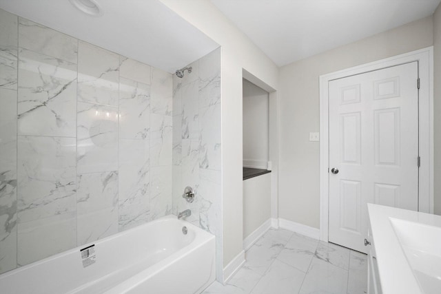 full bathroom featuring baseboards, marble finish floor, vanity, and washtub / shower combination