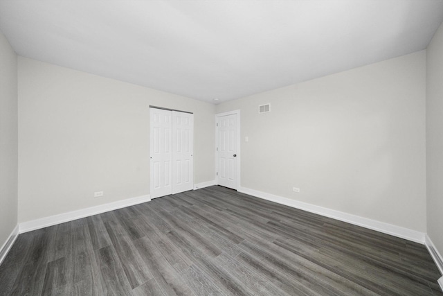 unfurnished room with baseboards, dark wood-style flooring, and visible vents