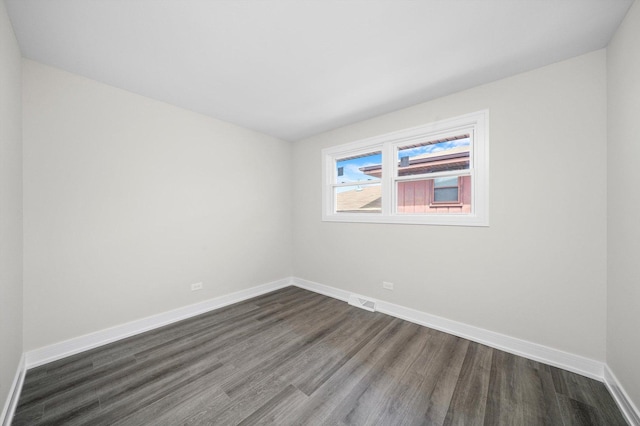 empty room featuring baseboards, visible vents, and dark wood-style floors