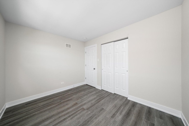unfurnished bedroom with baseboards, visible vents, and dark wood-style floors