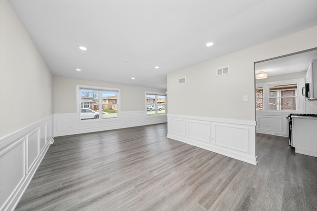 empty room featuring wainscoting, wood finished floors, visible vents, and recessed lighting