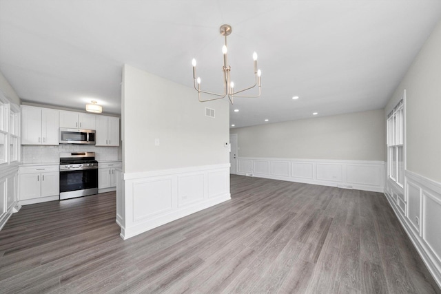 interior space featuring open floor plan, visible vents, a notable chandelier, wood finished floors, and appliances with stainless steel finishes