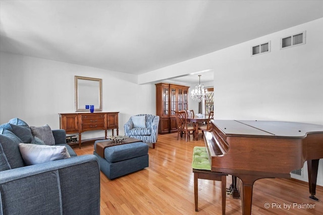 living room with a chandelier, visible vents, and light wood-type flooring