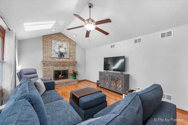 living room with vaulted ceiling with skylight, visible vents, and a ceiling fan