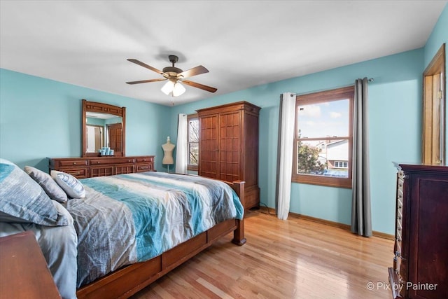 bedroom with light wood finished floors, baseboards, and a ceiling fan