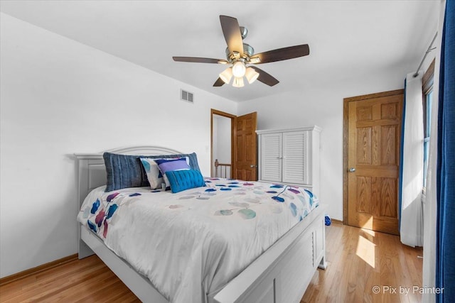 bedroom featuring light wood-style flooring, baseboards, a ceiling fan, and visible vents