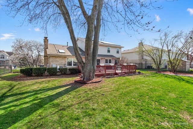 back of property featuring a yard, fence, a wooden deck, and a chimney