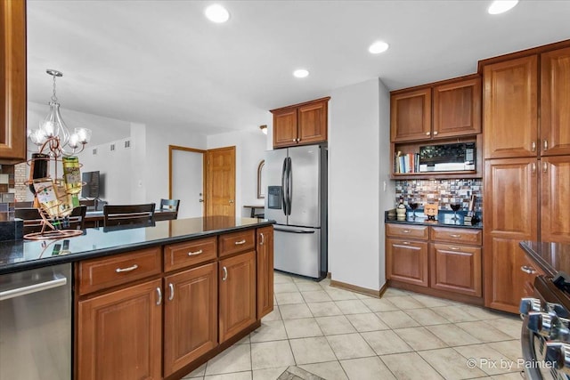 kitchen with brown cabinetry, a chandelier, appliances with stainless steel finishes, dark countertops, and decorative backsplash