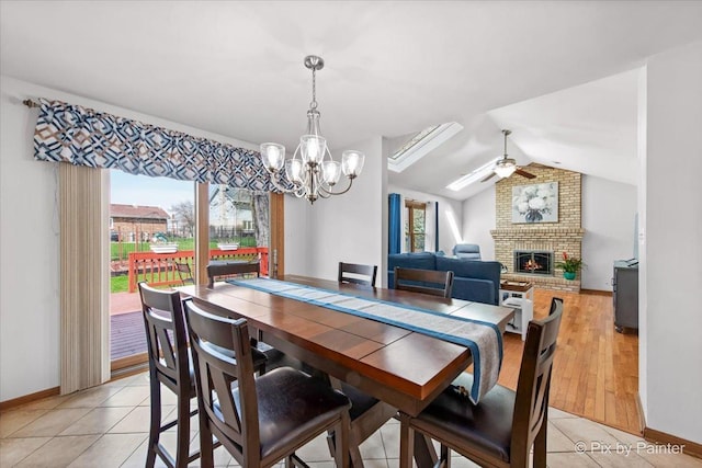 dining space featuring ceiling fan with notable chandelier, plenty of natural light, lofted ceiling, and a fireplace