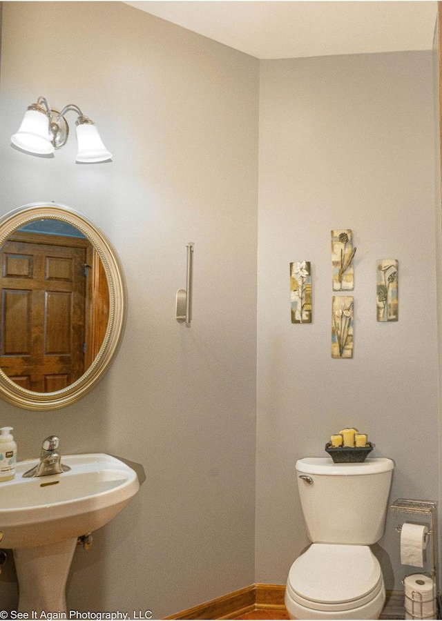 bathroom featuring a sink, baseboards, and toilet