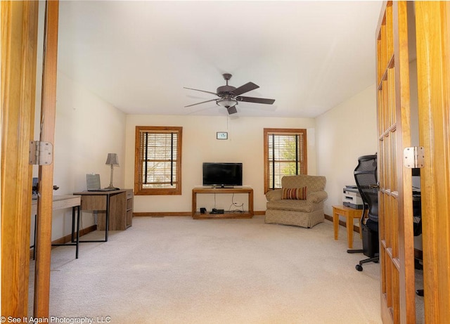 living area featuring light colored carpet, baseboards, and ceiling fan