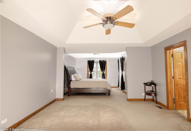 bedroom featuring baseboards, light colored carpet, and a raised ceiling