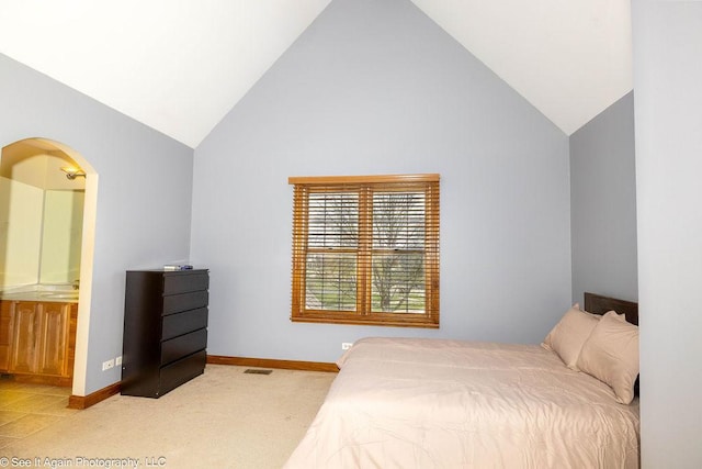 carpeted bedroom featuring arched walkways, high vaulted ceiling, baseboards, and ensuite bath