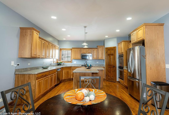 kitchen featuring a center island, light countertops, light wood finished floors, and stainless steel appliances