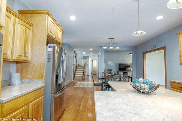 kitchen featuring light countertops, stainless steel refrigerator with ice dispenser, recessed lighting, and light wood finished floors