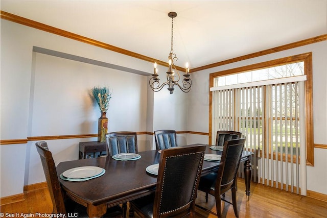 dining area featuring baseboards, a notable chandelier, a healthy amount of sunlight, and wood finished floors