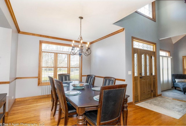 dining space featuring baseboards, a chandelier, ornamental molding, and light wood-type flooring