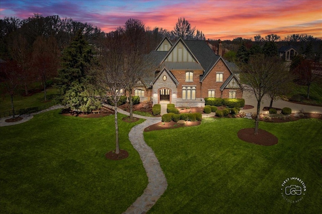 english style home featuring board and batten siding, stone siding, and a front yard