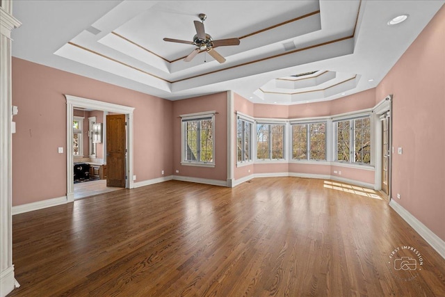 unfurnished living room with ceiling fan, baseboards, wood finished floors, and a raised ceiling