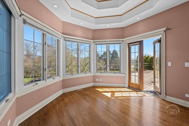 unfurnished sunroom with baseboards, wood finished floors, and plenty of natural light