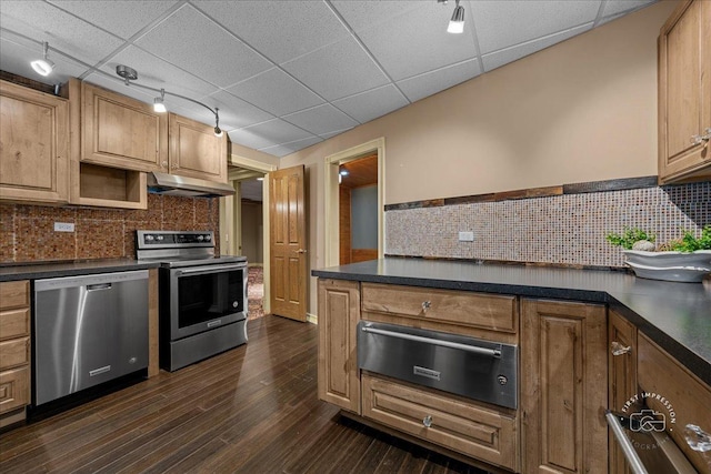 kitchen featuring dark countertops, under cabinet range hood, a warming drawer, appliances with stainless steel finishes, and a paneled ceiling