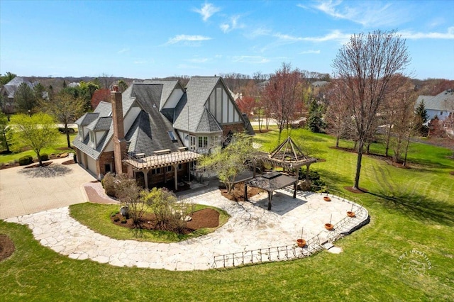 exterior space with a chimney, a pergola, a yard, driveway, and a garage