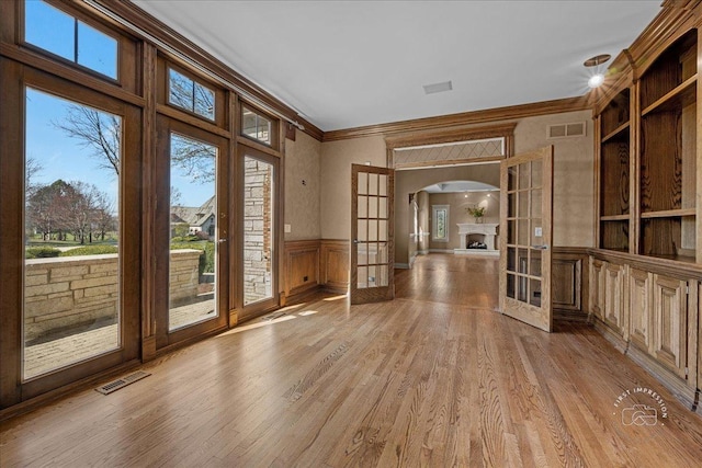 doorway to outside featuring arched walkways, crown molding, french doors, and visible vents