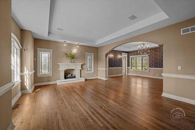 unfurnished living room with visible vents, a notable chandelier, and a raised ceiling
