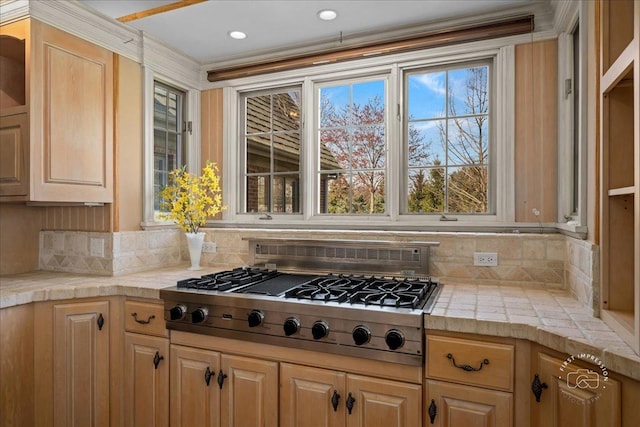 kitchen featuring stainless steel gas stovetop, decorative backsplash, and light brown cabinetry