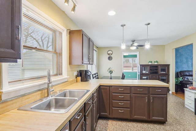 kitchen with a peninsula, light countertops, a ceiling fan, and a sink