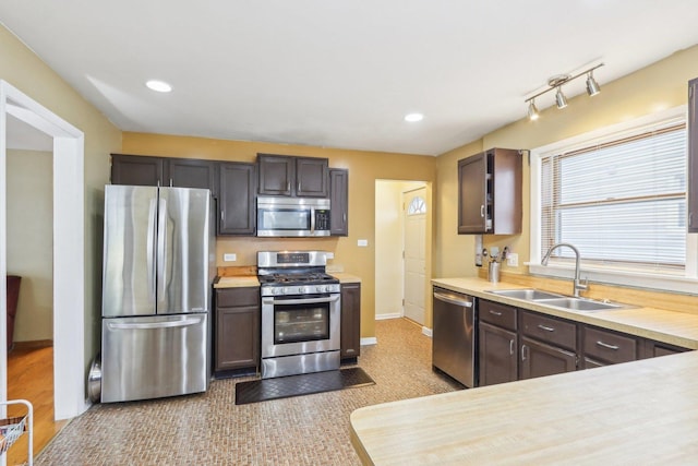 kitchen with recessed lighting, stainless steel appliances, light countertops, a sink, and baseboards