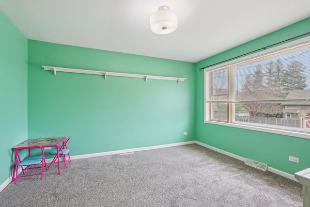 carpeted spare room featuring baseboards and visible vents