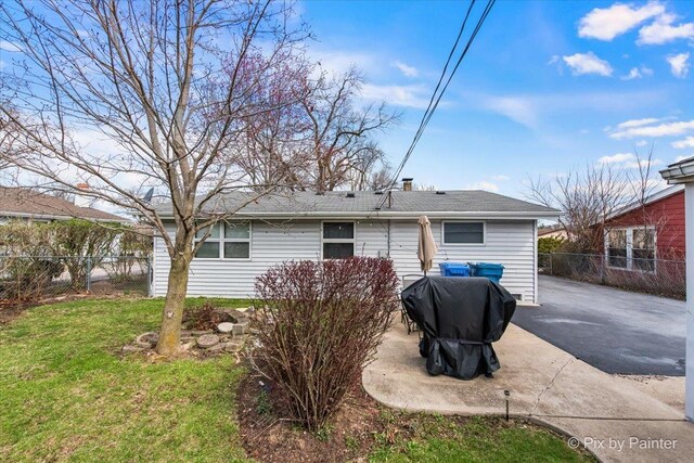 rear view of house with a patio area, a lawn, and fence