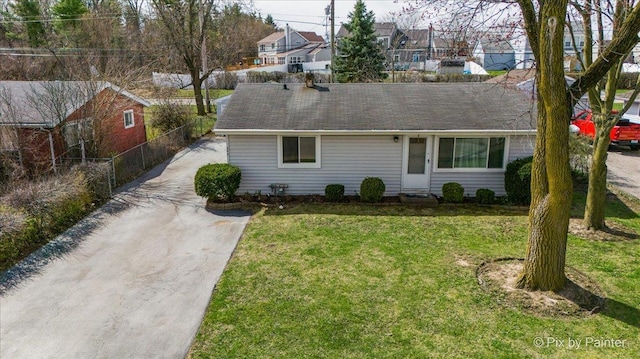view of front facade with driveway, fence, a residential view, and a front yard